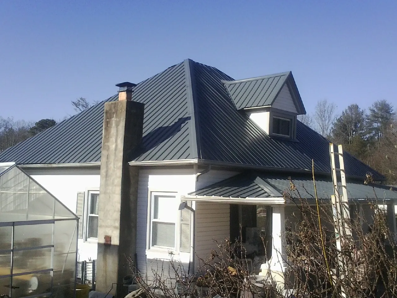 Dark blue standing seam metal roof on a white farmhouse with dormer — Slate & Tile Roof Repair by Roofing Brothers in Schenevus