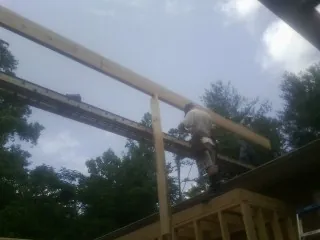 Carpenter setting a ridge beam over a new addition frame — Ice Dam Removal by Roofing Brothers in Schenevus