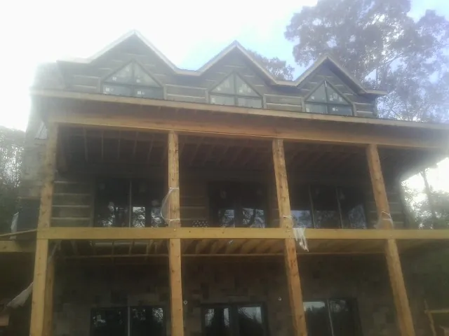 Dormers and porch framing on a large log home under construction — Roof Coating work by our crew in Schenevus