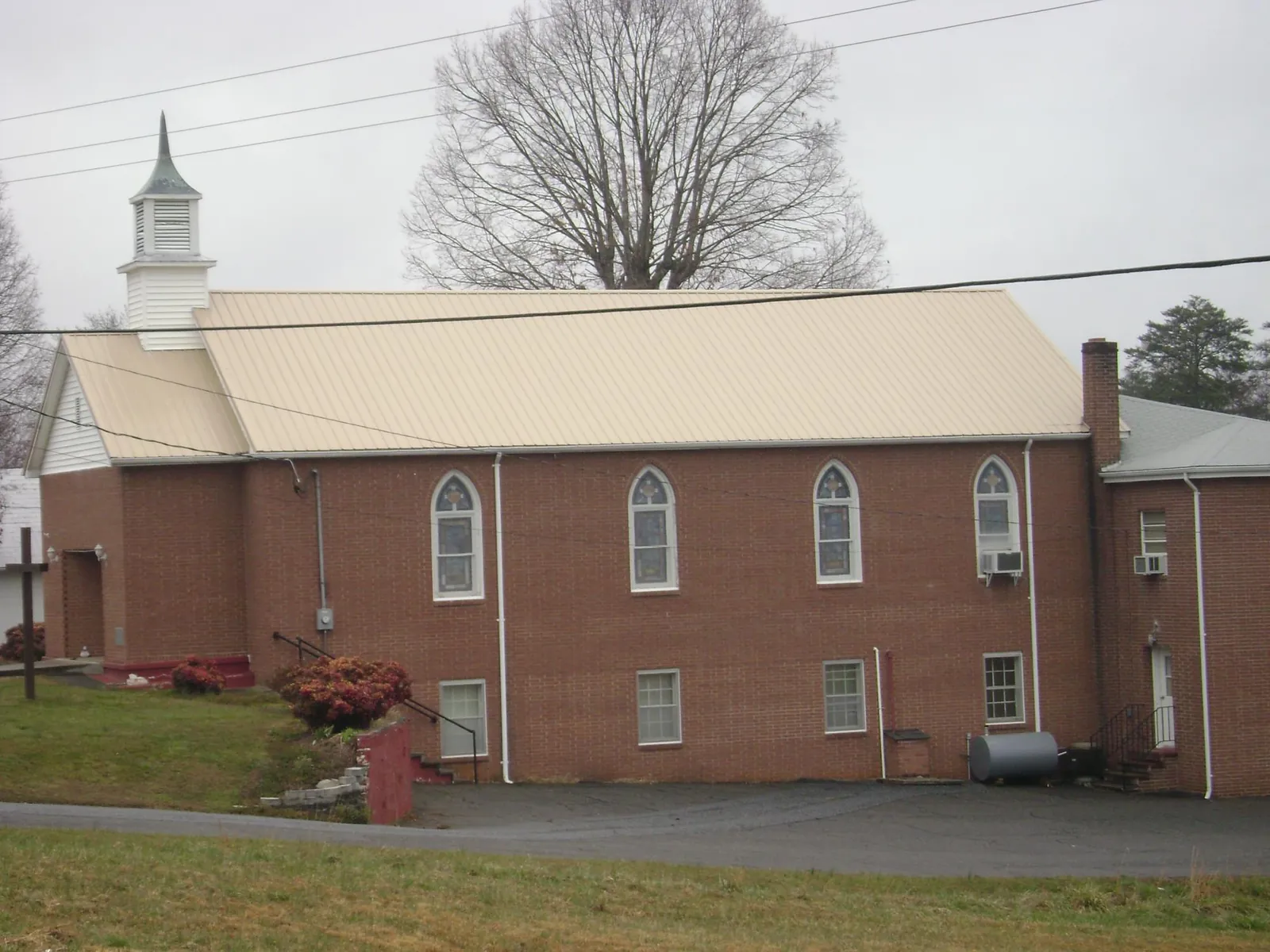 New tan metal roof on a brick church with a white steeple in Schenevus