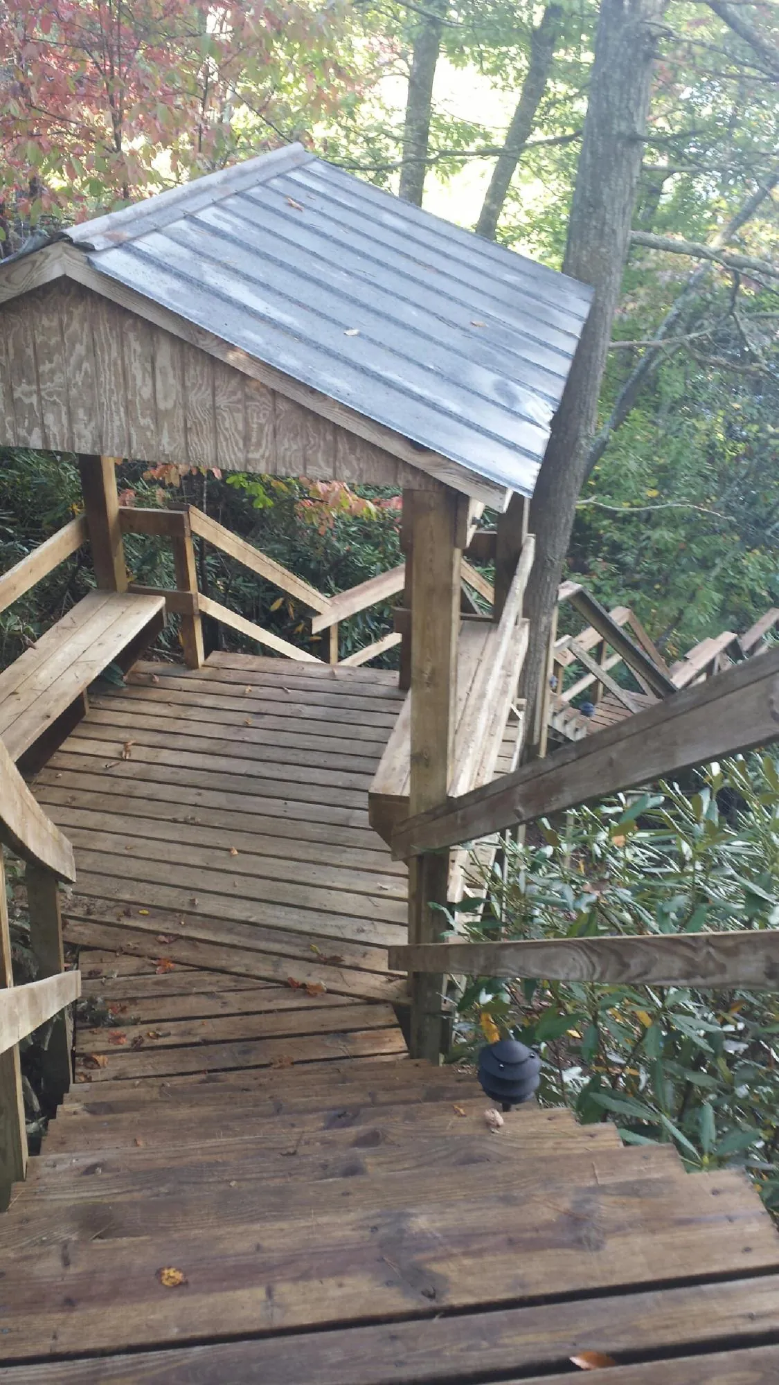 Metal roofed shelter over wooden steps on a wooded walkway — Skylight Repair & Installation work by our crew in Schenevus