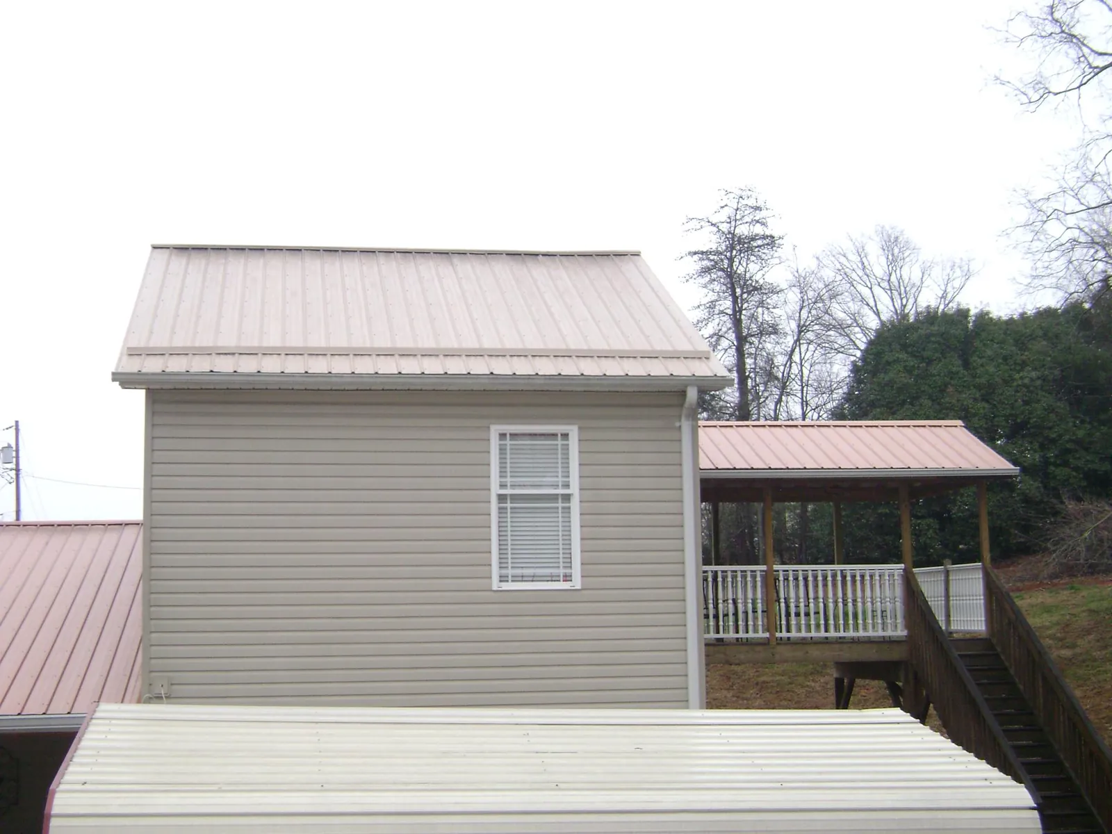 Tan metal roofs on a two story addition and attached porch, from a Roof Replacement job in Schenevus