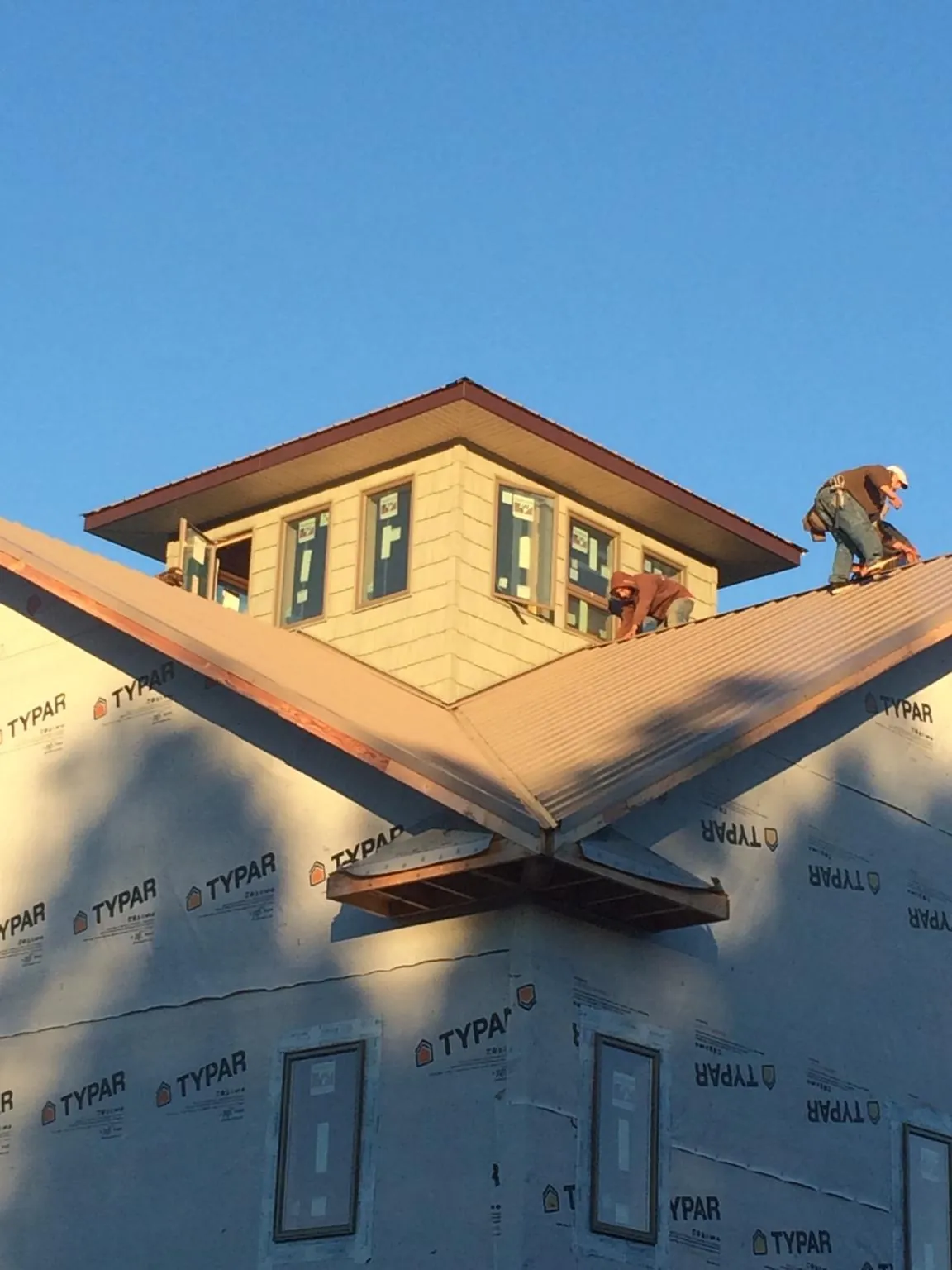 Roofers working around a rooftop cupola on a new metal roof at sunset — Roof Waterproofing in Schenevus by Roofing Brothers